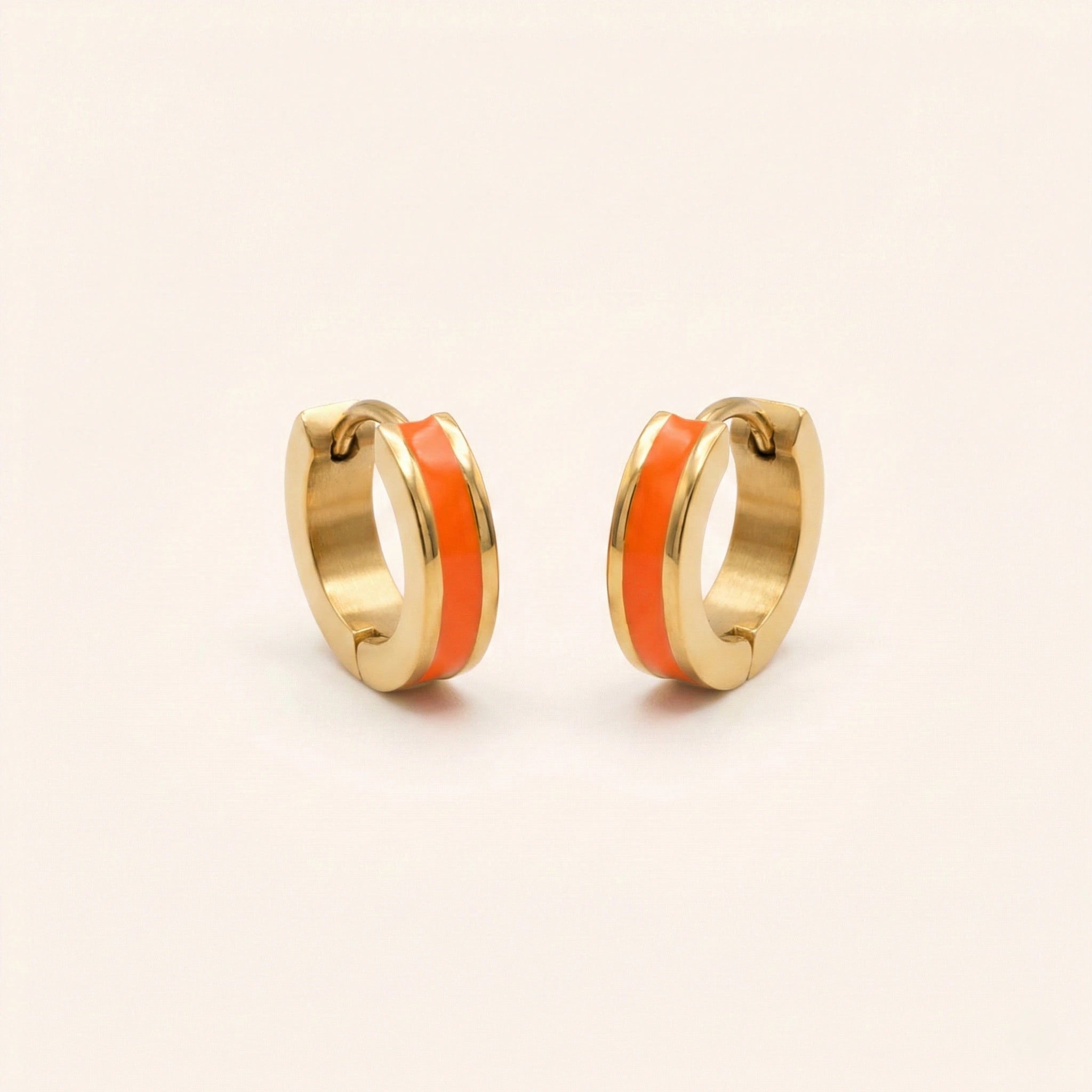 Gold hoop earrings with orange enamel stripes on a beige background